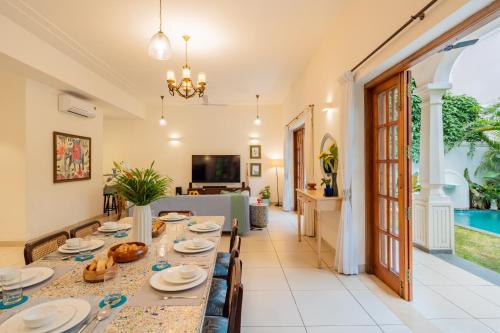 a dining room with a long table with plates and food at ELIVAAS 4 BHK with Pvt Pool near Baga - Celest in Old Goa