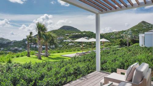 a patio with chairs and umbrellas with mountains in the background at Ideally located Prestigious Villa in Toiny