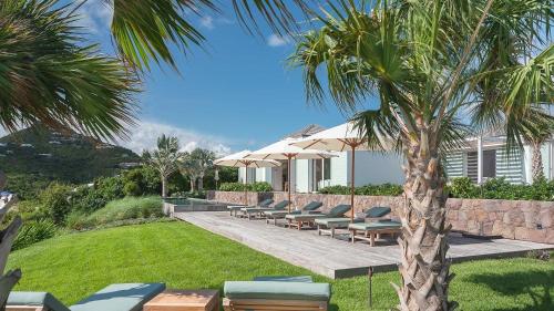 a group of chairs and umbrellas next to a house at Ideally located Prestigious Villa in Toiny