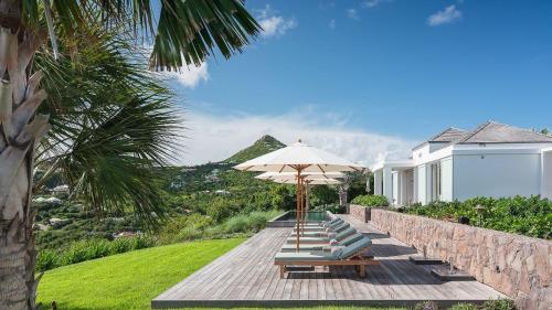 a group of lounge chairs and an umbrella at Ideally located Prestigious Villa in Toiny