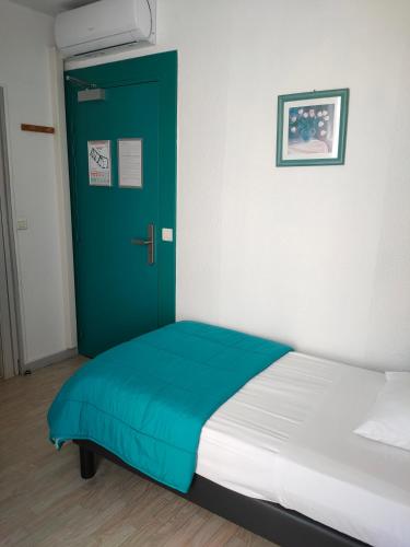 a bed in a room with a green door at Hôtel de la Grotte in Aix-les-Bains