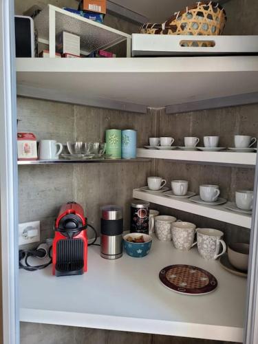 a shelf with cups and bowls and a red blender at Mountain Lake View Deluxe in Saint-Cergue