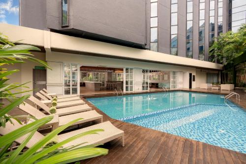 a swimming pool with chairs and a building at Meliá Kuala Lumpur in Kuala Lumpur