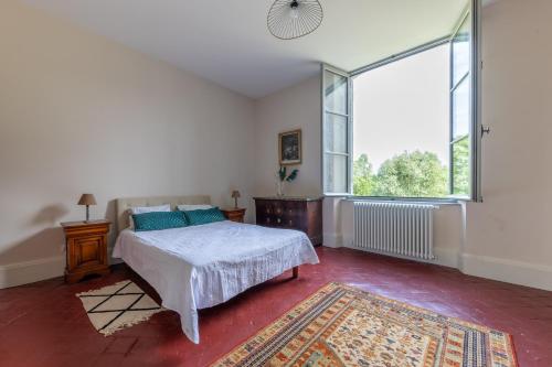 une chambre avec un lit et une grande fenêtre dans l'établissement Le Château de Marmagne - Belle maison de campagne, à Marmagne