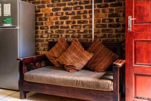 a bench with pillows on it next to a brick wall at ATKV Klein-Kariba in Bela-Bela