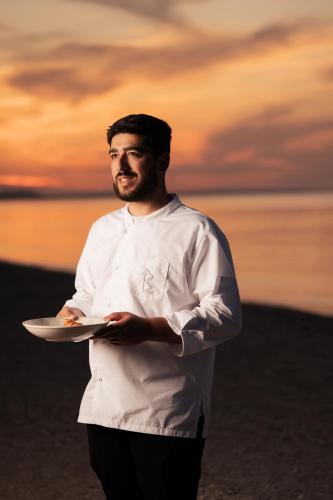 a man in a chef outfit holding a plate of food at Blue Carpet Luxury Suites in Pefkohori