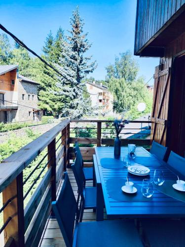 une table bleue et des chaises sur une terrasse avec vue dans l'établissement Appartement Chalet Cozy au pied des pistes!, à Saint-Pierre-dels-Forcats