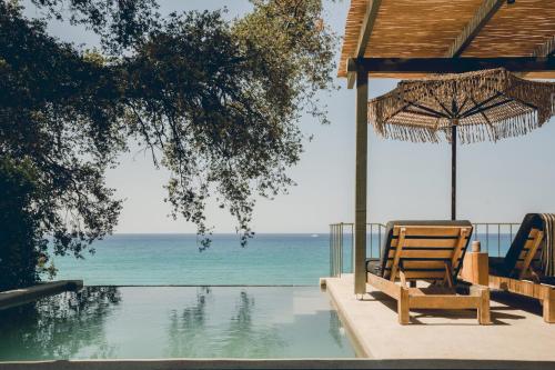 a pair of chairs and an umbrella next to a swimming pool at F ZEEN Kefalonia in Lourdhata