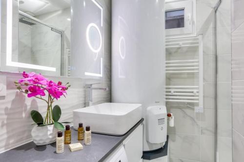 une salle de bain blanche avec un lavabo et un miroir dans l'établissement Bel appartement - 2 chambres au centre de Paris, à Paris