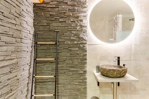 a bathroom with a sink and a stone wall at Le 36/Espace bien-être privatif in Bellevaux