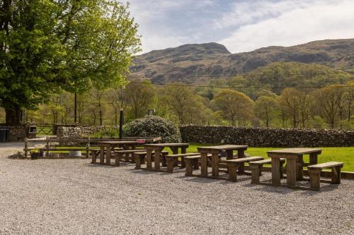 a row of wooden picnic tables in a park at Cosy Glamping In the Eskdale Valley - Studio Lodges and Mega Pods in Eskdale
