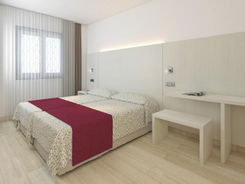 a white bedroom with a bed and a table at Apartaments Ses Dàlies in Port d'Alcudia