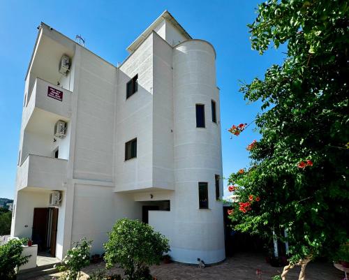 a white building with a tree in front of it at Jeti Guesthouse in Ksamil