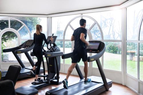 a man and woman exercising on treadmills in a gym at L'Albereta Relais & Chateaux in Erbusco