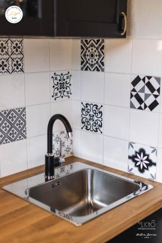 - un évier en acier inoxydable dans une cuisine revêtue de carrelage noir et blanc dans l'établissement Appartement - Label Dévoluy 4 diamants, à Saint-Étienne-en-Dévoluy