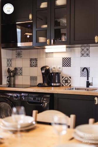 - une cuisine avec des placards noirs et un évier dans l'établissement Appartement - Label Dévoluy 4 diamants, à Saint-Étienne-en-Dévoluy