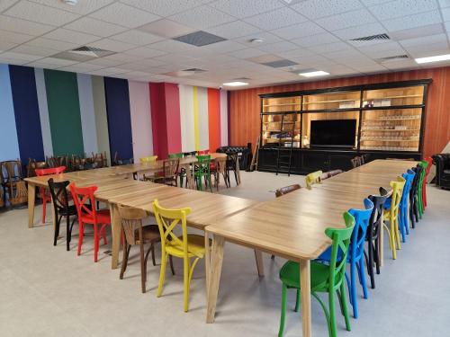 a large room with wooden tables and colorful chairs at Beelodge Hotel Blois Centre in Blois