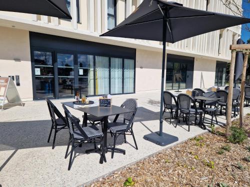 a group of tables and chairs with an umbrella at Beelodge Hotel Blois Centre in Blois