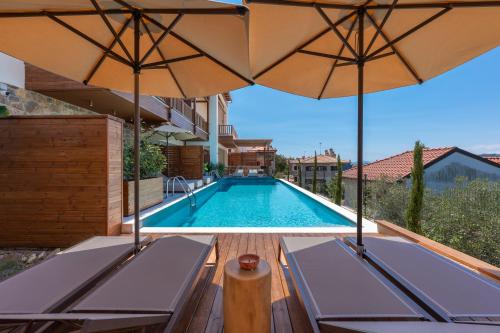 a swimming pool with two chairs and two umbrellas at Anima Residence in Nea Roda