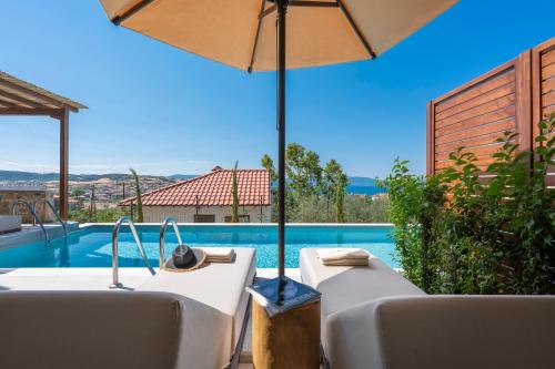 a villa with a swimming pool and an umbrella at Anima Residence in Nea Roda