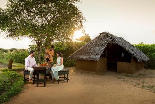 a group of people sitting at a table in front of a hut at Jetwing Jungle Lodge, A Luxury Reserve in Yala