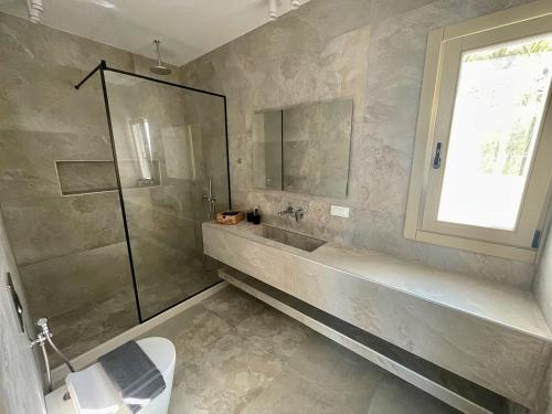 a bathroom with a shower and a toilet and a sink at Casa Suites Mykonos in Agios Stefanos