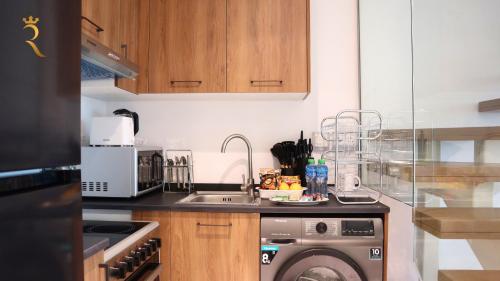 a kitchen with a sink and a washing machine at Plush 2BR Retreat in Masdar City - Modern Stay Near Masdar Park & City Centre in Abu Dhabi