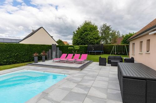 un patio avec des chaises roses et une piscine dans l'établissement Villa avec piscine chauffée proche circuit 24h, à Loué