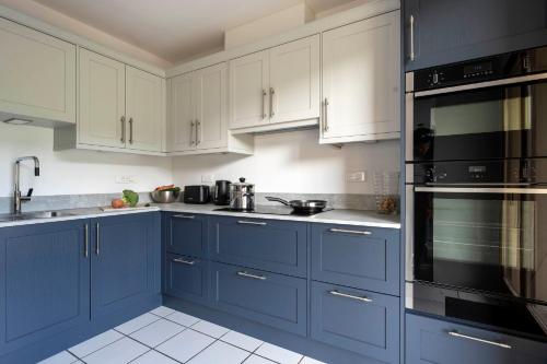 une cuisine bleue avec des armoires blanches et des appareils noirs dans l'établissement Chalet Les Cyclamens, aux Gets