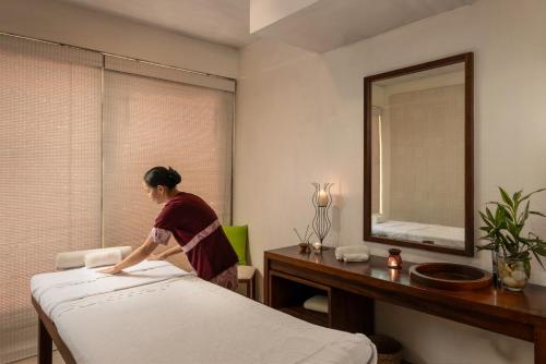 a woman making a bed in a hotel room at Jetwing Blue in Negombo