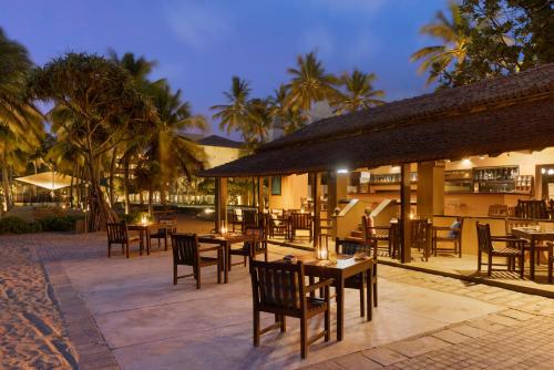 a restaurant with tables and chairs and palm trees at Jetwing Blue in Negombo