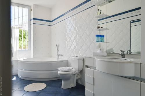 La salle de bains blanche est pourvue d'une baignoire, de toilettes et d'un lavabo. dans l'établissement Villa Emma au coeur de Malmousque, à Marseille