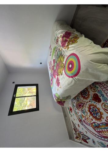 - un lit avec une couette colorée et une fenêtre dans l'établissement Villa prestige, à Florensac