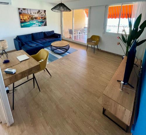 un salon avec un canapé bleu et une table dans l'établissement VUE EXCEPTIONNELLE - Ajaccio T3 rte Sanguinaires - Santa Lina, à Ajaccio