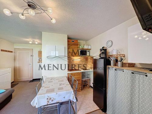 Il comprend une cuisine équipée d'un réfrigérateur noir et d'une table. dans l'établissement Appartement 2 pièces, 4 pers, ski aux pieds, balcon, parking gratuit - FR-1-178-374, aux Menuires