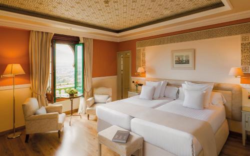 a hotel room with a large bed and a window at Alhambra Palace Hotel in Granada