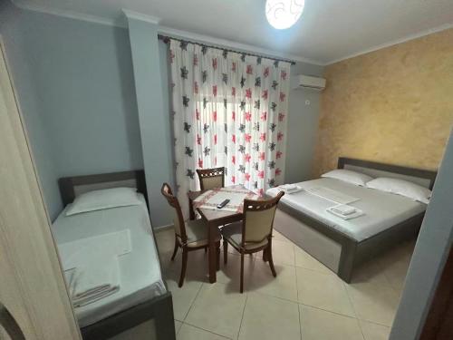a room with two beds and a table and chairs at Jeti Guesthouse in Ksamil