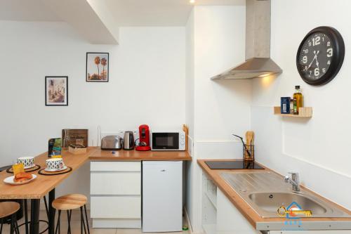 une cuisine avec un évier et une horloge murale dans l'établissement Le cocon centre ville au calme Oc Keys 34, à Castelnaudary