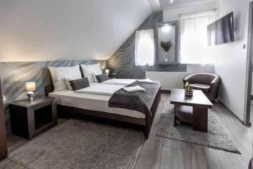 a bedroom with a bed and a chair and a table at Royal Apartments Hotel Kecskemét in Kecskemét