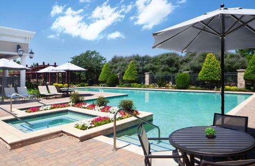a swimming pool with a table and an umbrella at Hilton Dallas Southlake Town Square in Southlake