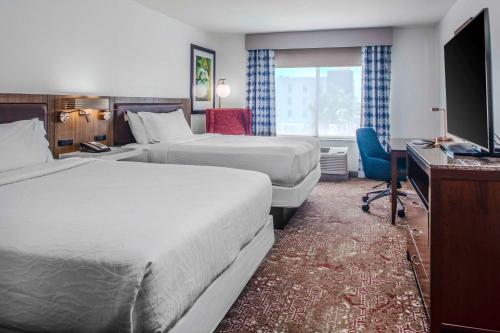 a hotel room with two beds and a desk and a television at Hilton Garden Inn Sarasota-Bradenton Airport in Sarasota
