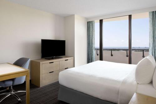 a hotel room with a bed and a flat screen tv at Embassy Suites by Hilton Tampa Airport Westshore in Tampa