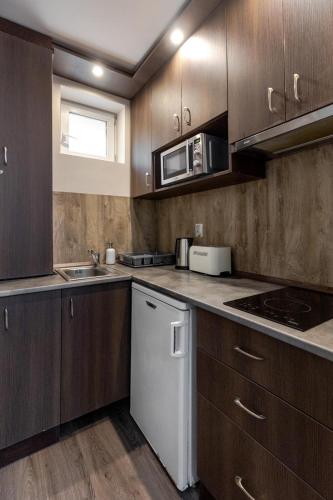 a kitchen with wooden cabinets and a microwave at Royal Apartments Hotel Kecskemét in Kecskemét