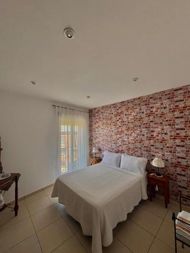 a bedroom with a large white bed with a brick wall at Casa Rural El Lio in Ruidera