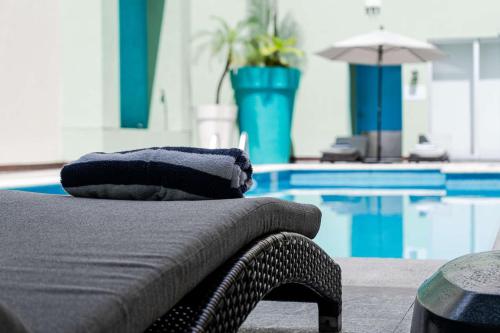 a chair with pillows sitting next to a swimming pool at Hampton by Hilton Veracruz Boca Del Rio in Veracruz