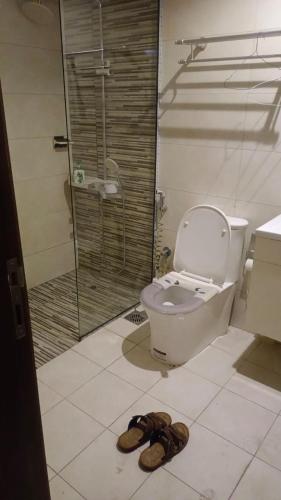 a bathroom with a toilet and a shower and a pair of shoes at DraGon Executive Homes 002 in Dubai