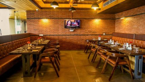 a dining room with tables and chairs and a tv at Oro Montana Hotels and Resort in Gangtok