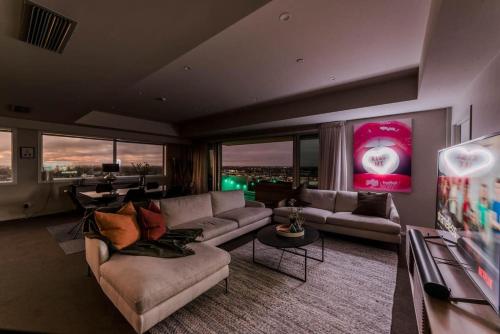 a living room with couches and a view of a city at Sleep Amongst the Clouds - Panoramic Views in Christchurch