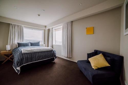 a bedroom with a bed and a couch and a window at Sleep Amongst the Clouds - Panoramic Views in Christchurch