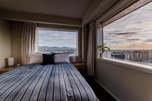 a bed in a room with a large window at Sleep Amongst the Clouds - Panoramic Views in Christchurch